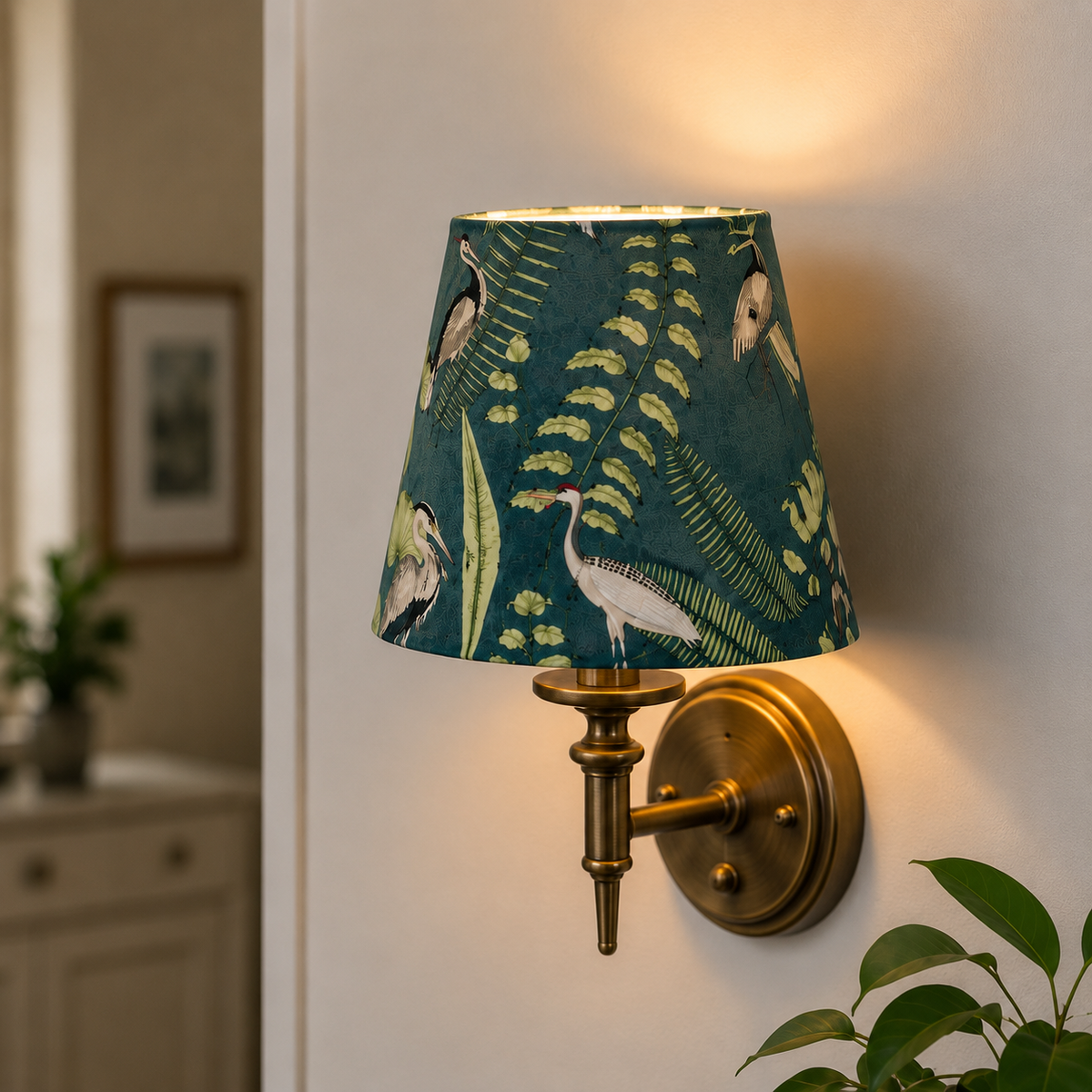 A wall lamp with a dark teal-green shade featuring a white heron and green tropical leaf pattern