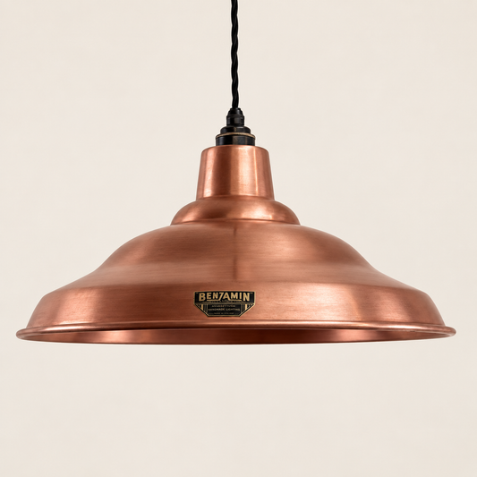 A copper pendant light with a wide, shallow dome shade, a black hanging cord, and a small metallic Benamin brand plaque on the front, set against a solid off-white background.
