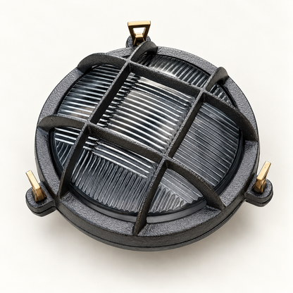 A round dark grey cast-iron outdoor light fixture with a protective cross-bar grille and brass mounting hardware, shown on a clean off-white background.