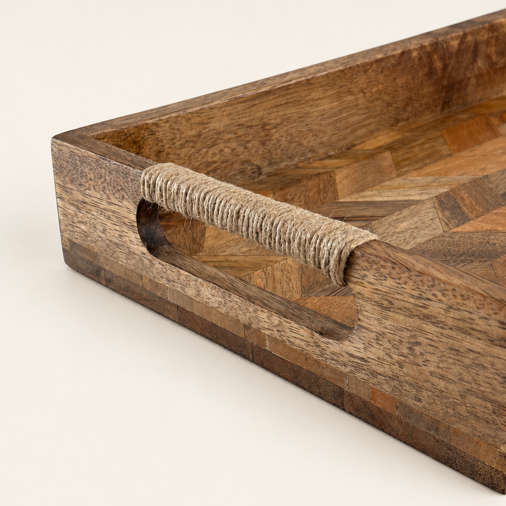 A close-up of a wooden serving tray with a geometric parquetry pattern and a natural fiber-wrapped handle, set against a plain off-white background.