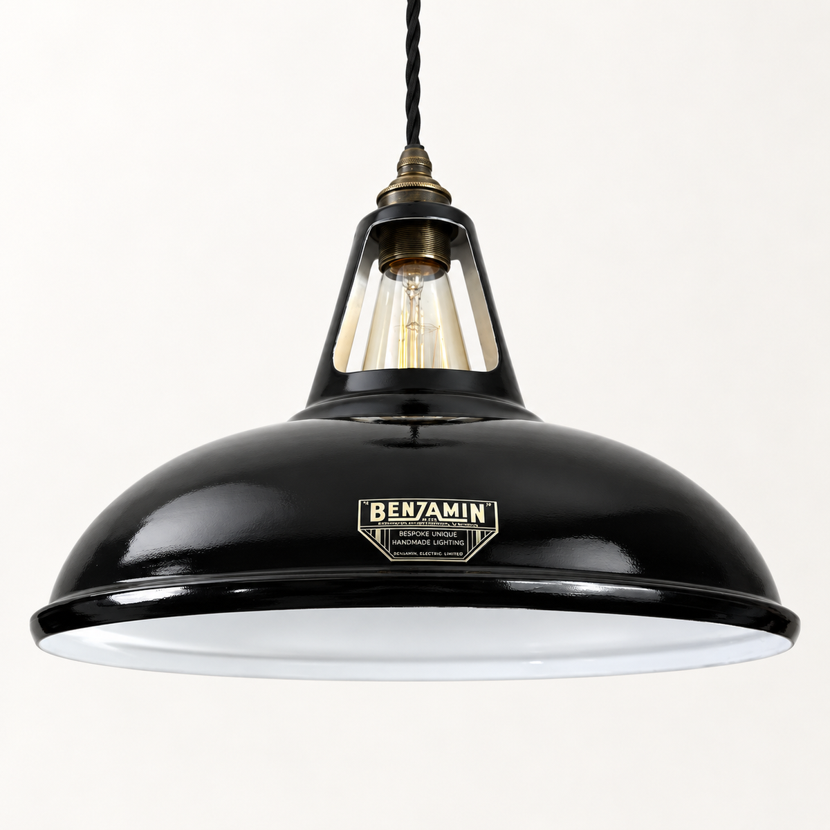 A black metal pendant light with a white enamel diffuser inside the dome shade, featuring a brass-toned neck and a vintage-style BENJAMIN brand plaque on the front.