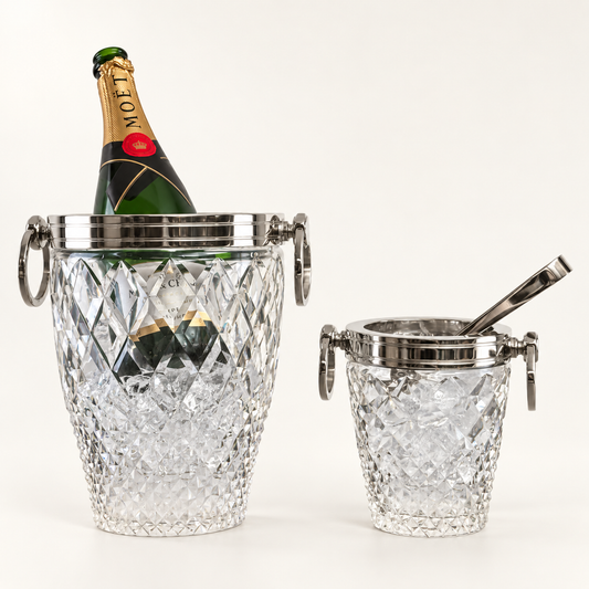 Two clear cut-crystal champagne buckets with silver-tone metal lids and handles, one holding a Moët & Chandon champagne bottle and one empty with a metal spoon, photographed on a clean white background.