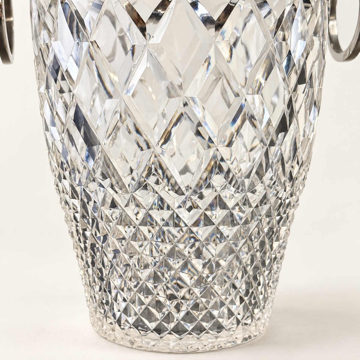 A close-up of a clear cut-crystal or glass bucket with a diamond-patterned faceted design and silver-tone metal handles visible at the top edges, set against a clean white background.