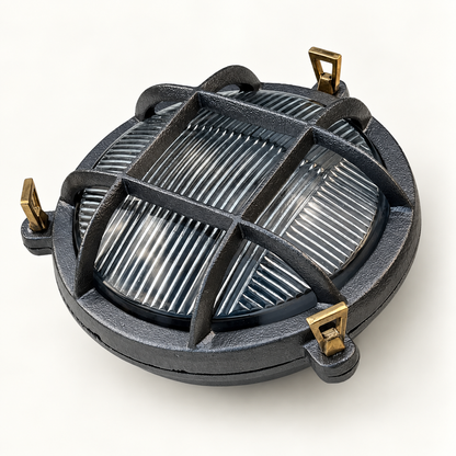 A round dark grey cast style outdoor light fixture with a protective cage and gold-toned mounting brackets, shown on a clean white background.