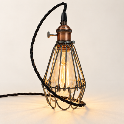 Hemsby raw steel cage lamp with copper finish holder and black fabric cable, illuminated in the studio