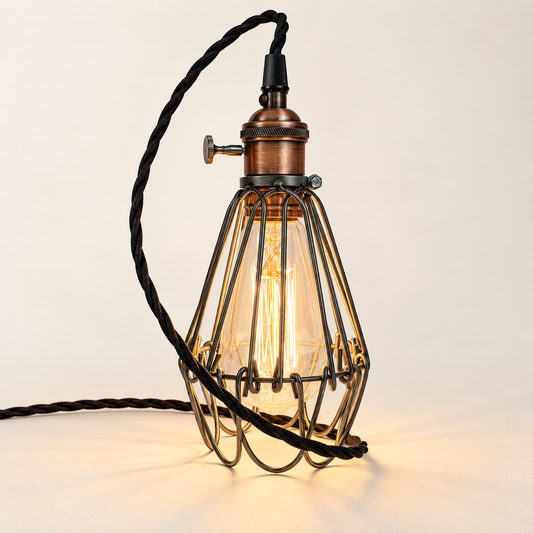 Hemsby raw steel cage lamp with copper finish holder and black fabric cable, illuminated in the studio