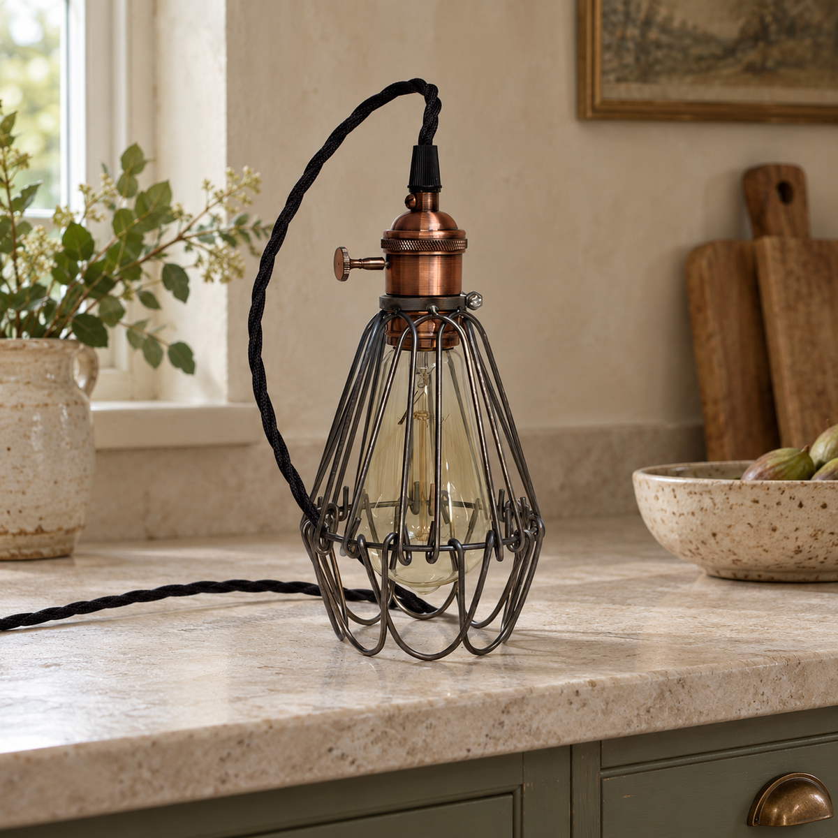Unlit Hemsby raw steel cage table lamp with copper finish holder and black cable on a limestone kitchen worktop