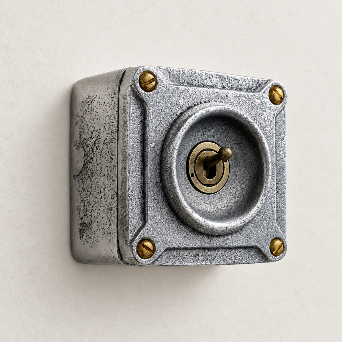 1-gang raw metal toggle light switch with brass details, angled studio view.