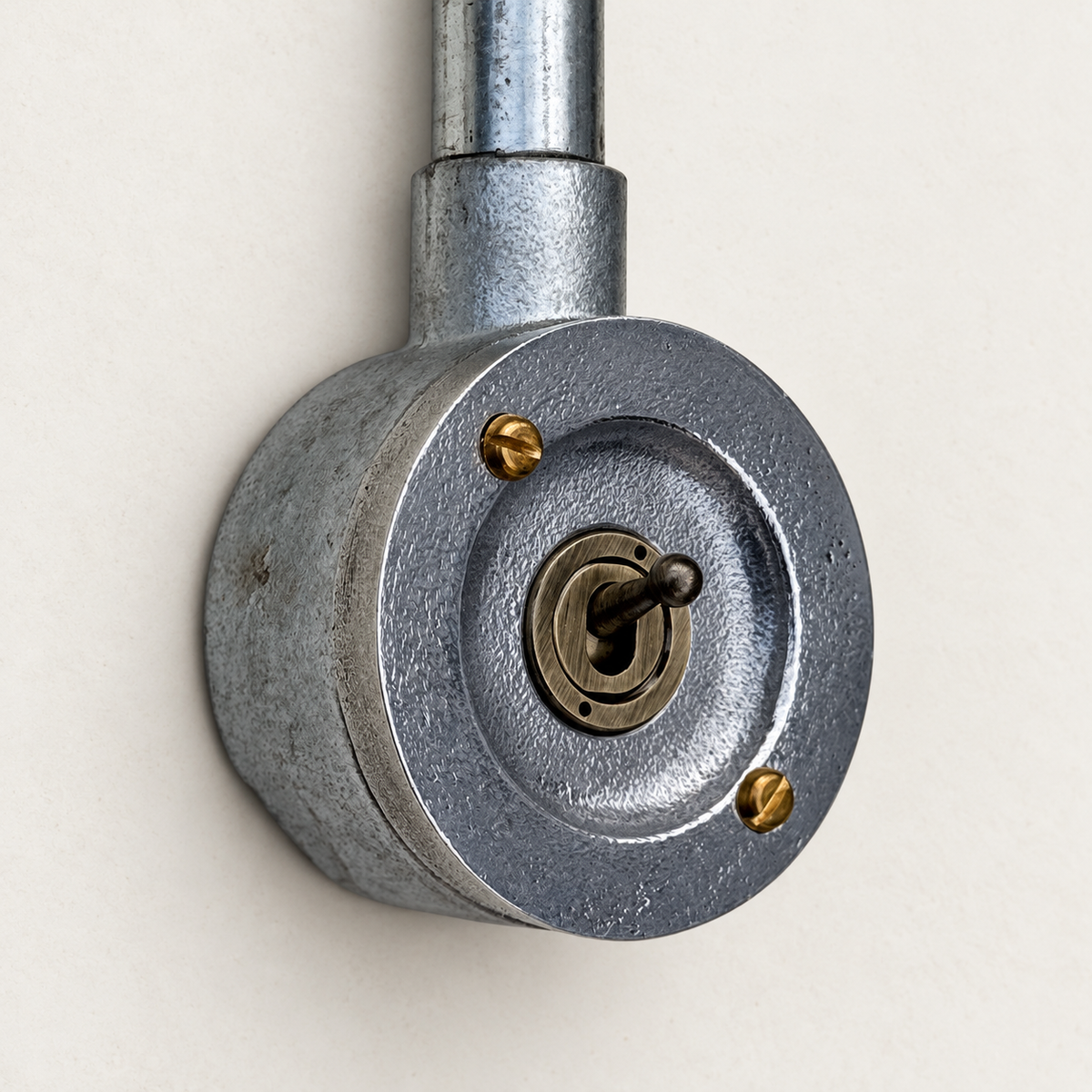1-gang raw metal round conduit toggle light switch, angled studio view.