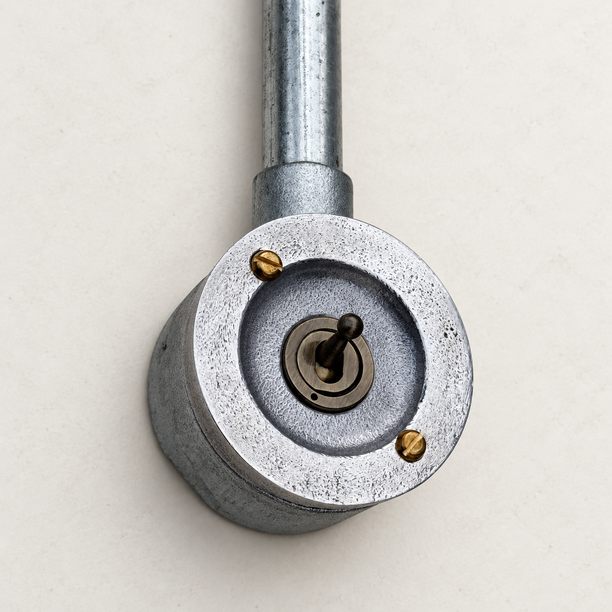 1-gang raw metal round conduit toggle light switch, elevated studio view.