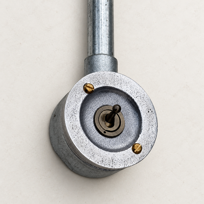 1-gang raw metal round conduit toggle light switch, elevated studio view.